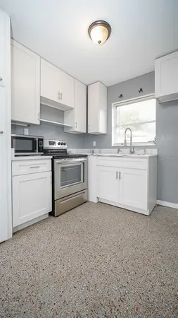 a kitchen with stainless steel appliances granite countertop a stove a sink and white cabinets