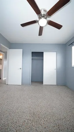 an empty room with a ceiling fan and a window