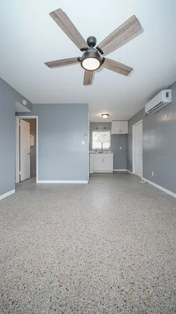 an empty room with chandelier fan and windows