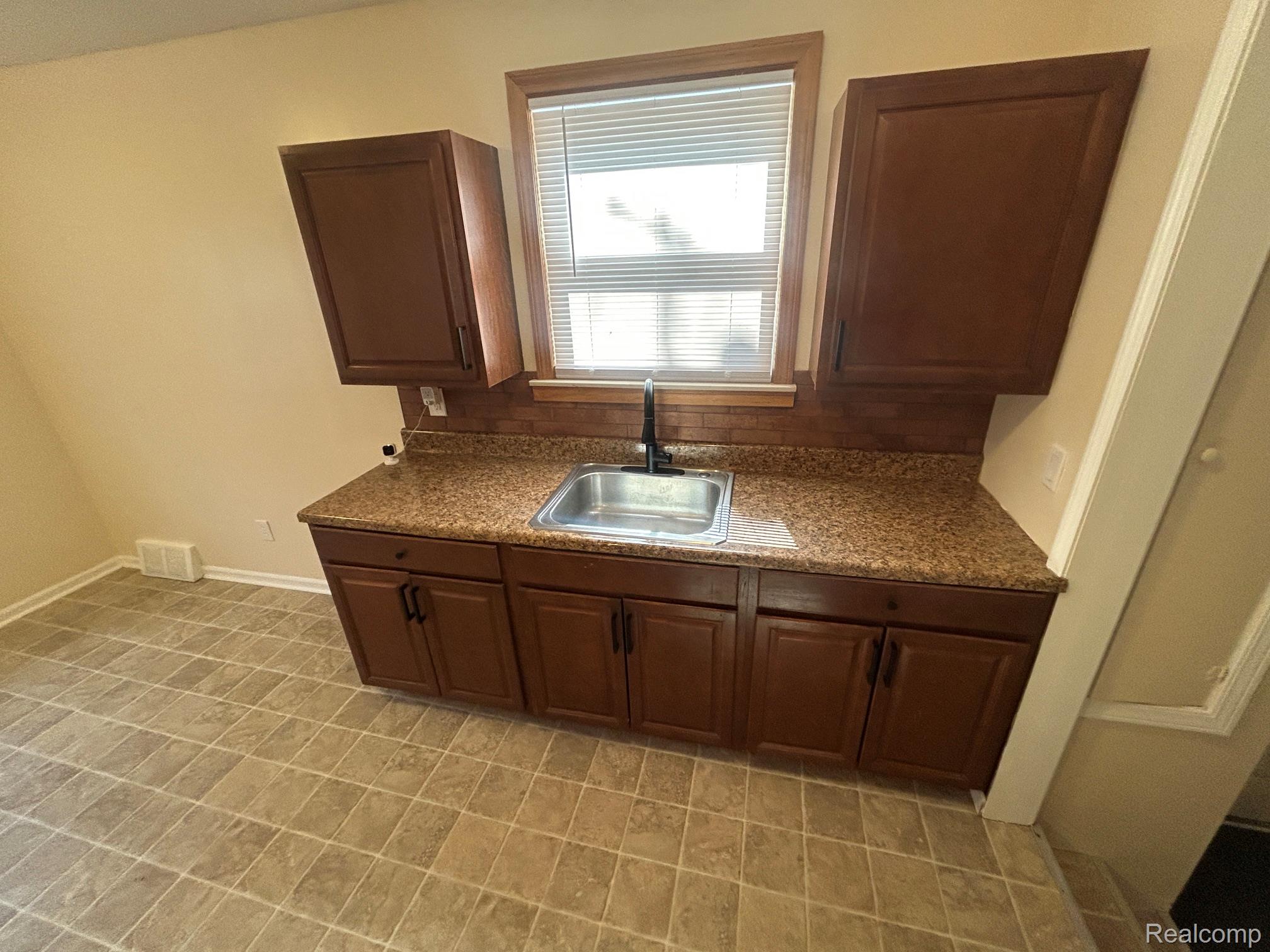 21970 Moross Road Grosse Pointe, MI 48236 - Photo 6 of 21 Kitchenette with a stainless steel sink and a black single-handle faucet, set into a granite-look countertop