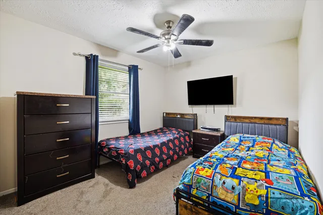 a bedroom with two beds and a flat tv screen on dresser