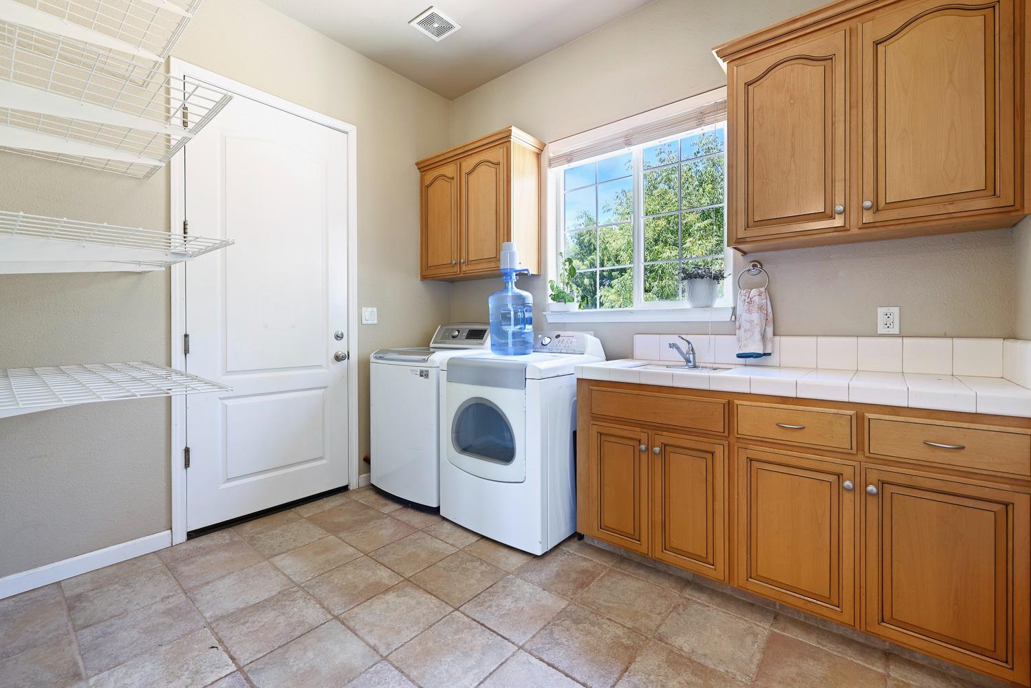 16787 Monreal Road Madera, CA 93636 - Photo 13 of 35 a utility room with cabinets washer and dryer