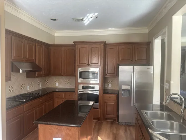 a kitchen with kitchen island granite countertop a sink appliances and cabinets
