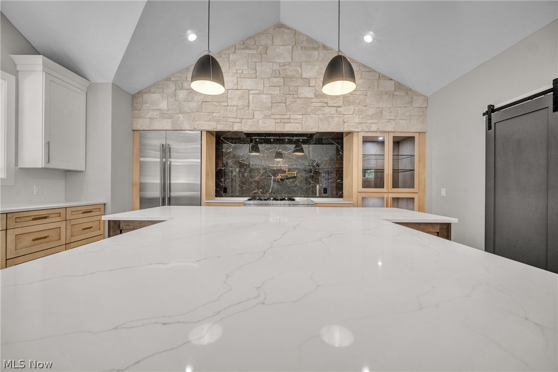 4009 Brainard Road Beachwood, OH 44122 - Photo 17 of 50 Kitchen with light stone counters, hanging light fixtures, a barn door, white cabinetry, and built in refrigerator