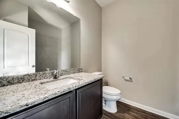 a bathroom with a granite countertop sink a toilet and a mirror
