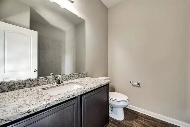 a bathroom with a granite countertop sink a toilet and a mirror