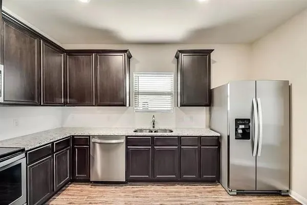 a kitchen with granite countertop wooden cabinets stainless steel appliances and a sink