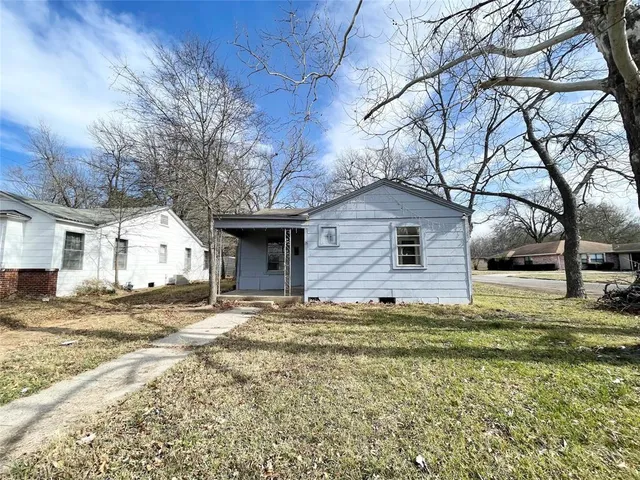 a view of a yard in front of a house with large tree