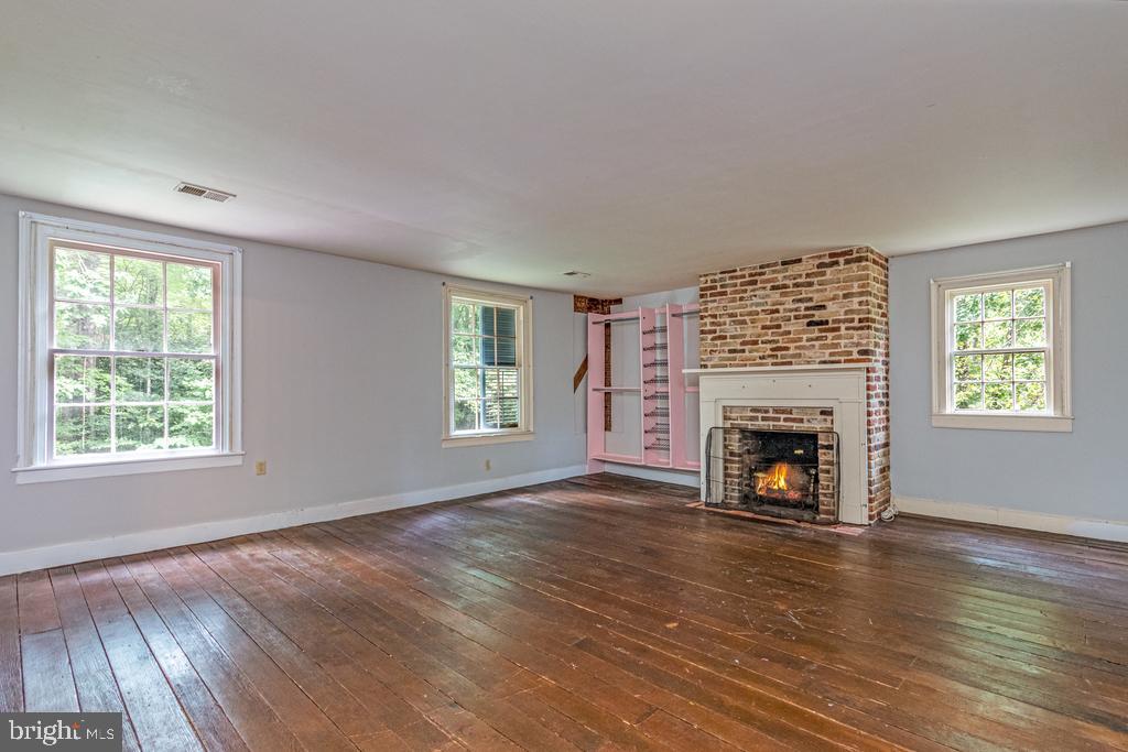807 Holly Corner Road Fredericksburg, VA 22406 - Photo 18 of 57 an empty room with windows a fireplace and wooden floor