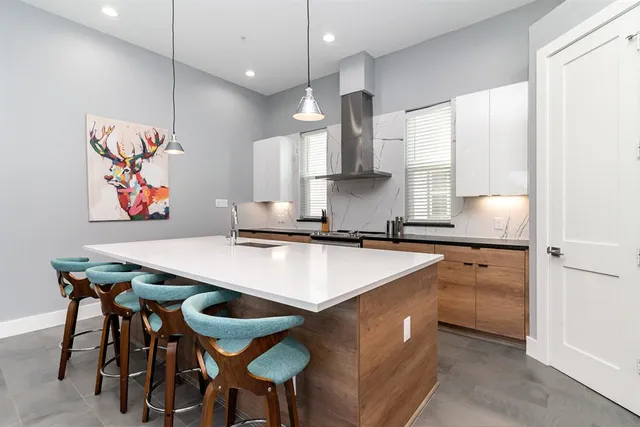 a kitchen with stainless steel appliances granite countertop a sink a stove a refrigerator and island with wooden floor