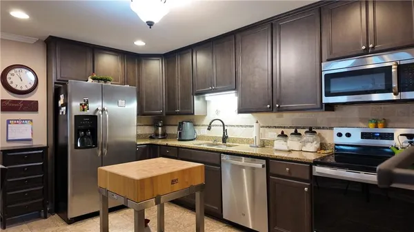 a kitchen with stainless steel appliances granite countertop a sink stove and refrigerator