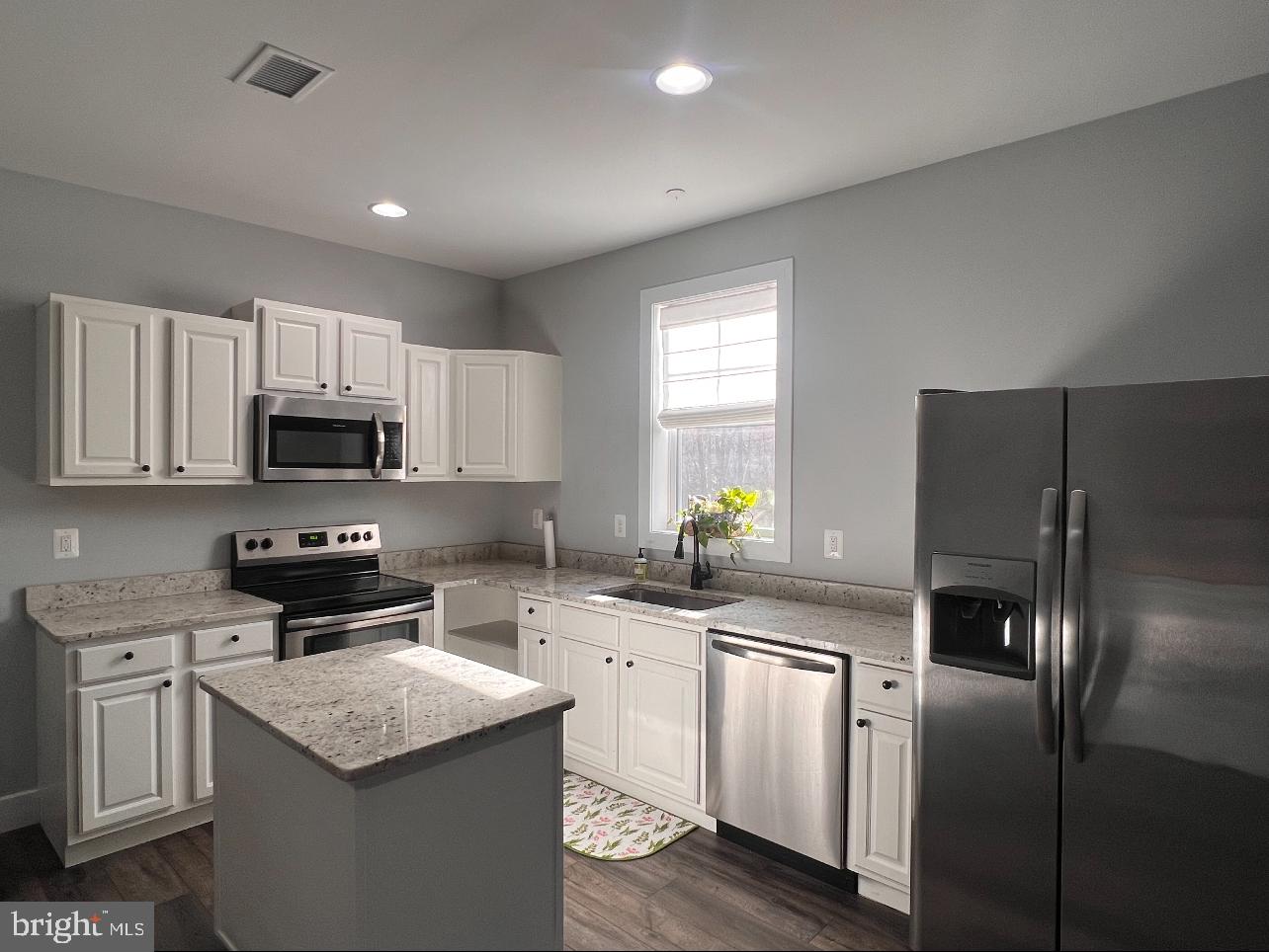 a kitchen with stainless steel appliances granite countertop a stove a sink a refrigerator a microwave and cabinets