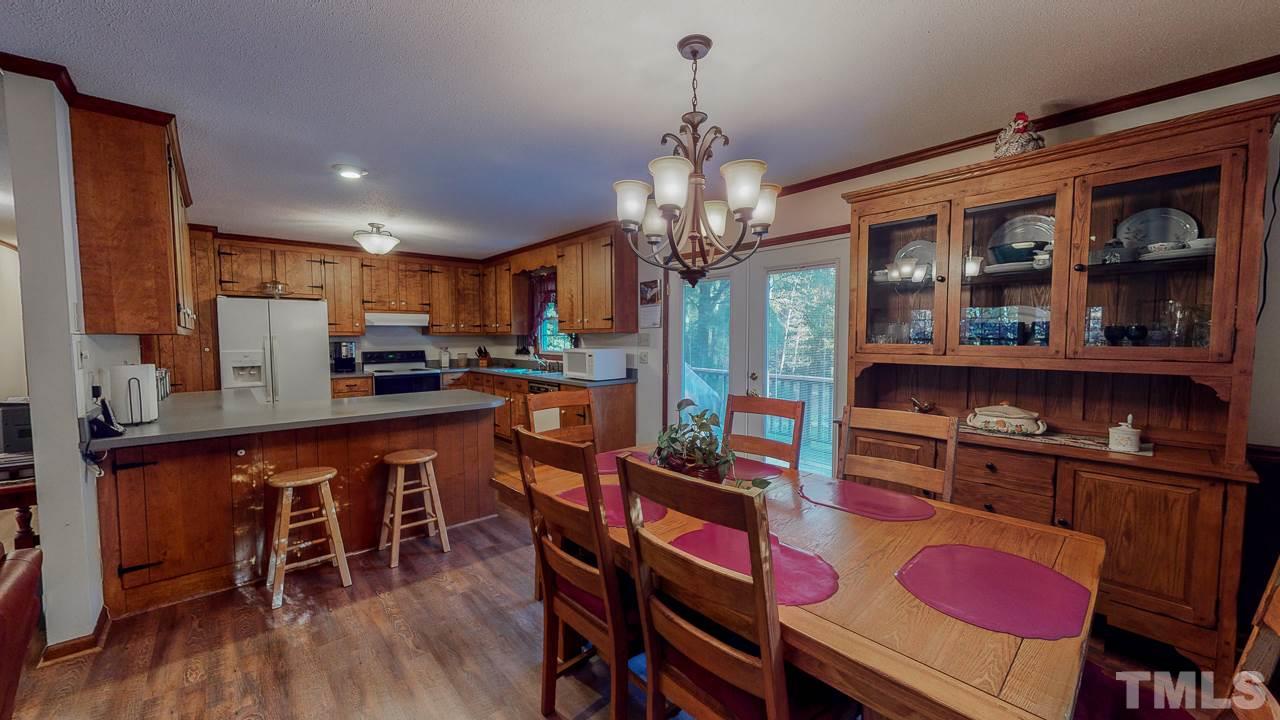 1307 Bill Poole Road Rougemont, NC 27572 - Photo 4 of 30 a kitchen with stainless steel appliances granite countertop a refrigerator a stove and a dining table with wooden floor