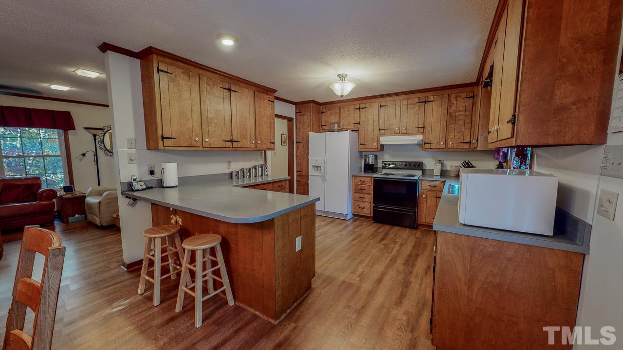 1307 Bill Poole Road Rougemont, NC 27572 - Photo 5 of 30 a kitchen with wooden cabinets a sink a stove and a refrigerator