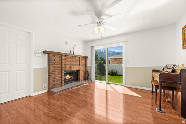 1650 Nichole Circle Sandy, UT 84093 - Photo 9 of 31 Living space featuring wood-finish flooring, a brick fireplace with a wood mantel, and a ceiling fan