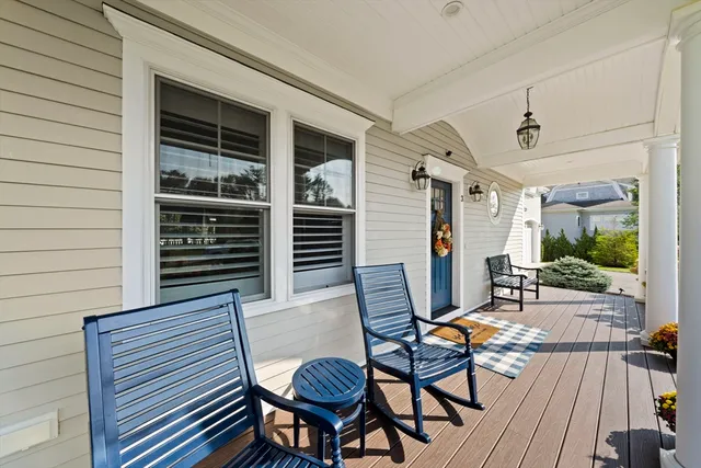 a balcony with table and chairs and potted plants