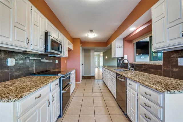 a large kitchen with stainless steel appliances granite countertop a stove a sink and a microwave