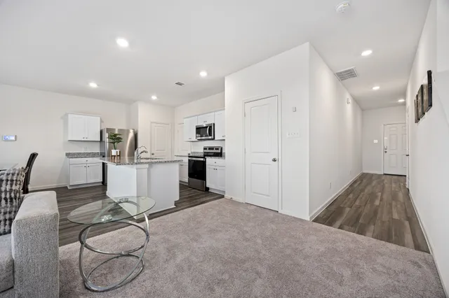 a room with stainless steel appliances kitchen island granite countertop a refrigerator and cabinets