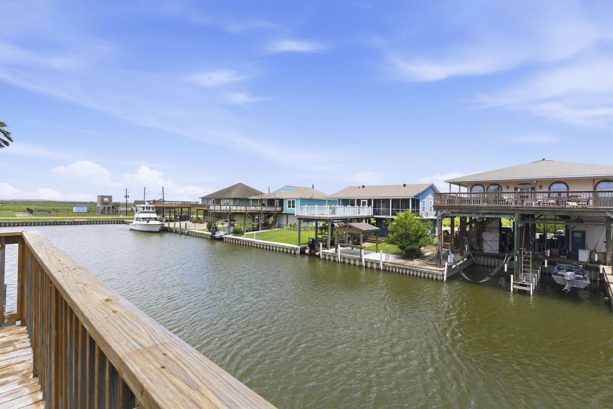 119 Sand Shoals Road Freeport, TX 77541 - Photo 12 of 34 Long canal view from dock — wide-deep canal positioned for direct out-flow, neighboring covered boat slips with lifts, and a private boat slip ready for the next owner.