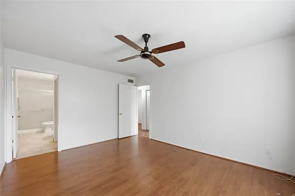an empty room with wooden floor and ceiling fan