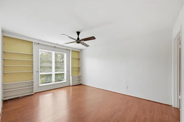 a view of an empty room with a window and wooden floor
