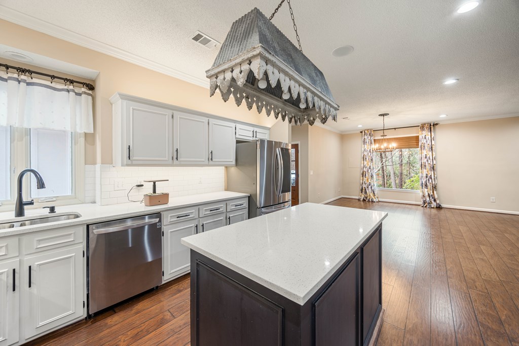 717 Double Churches Road Columbus, GA 31904 - Photo 35 of 54 a kitchen with a stove a sink dishwasher a refrigerator and white cabinets with wooden floor