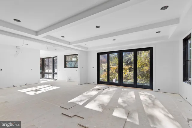 a view of an empty room with window and a kitchen