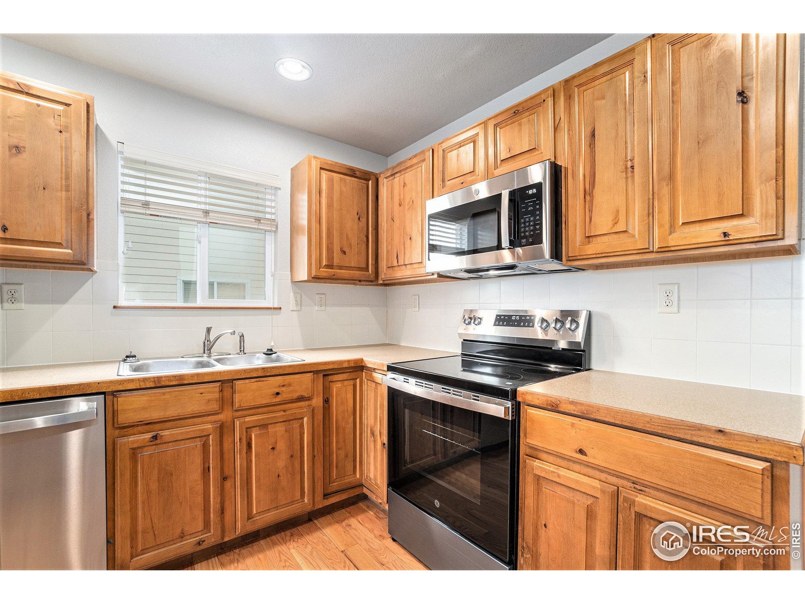 3474 Iron Horse Way Wellington, CO 80549 - Photo 7 of 20 a kitchen with stainless steel appliances granite countertop a sink stove and microwave
