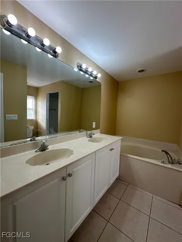 a bathroom with a tub a sink and mirror