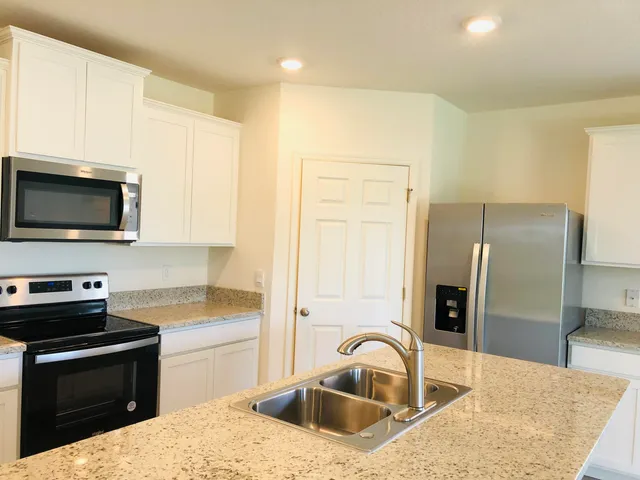 a kitchen with granite countertop a sink stainless steel appliances and cabinets