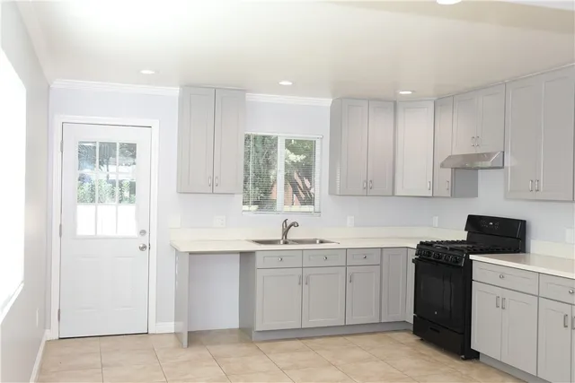 a kitchen with white cabinets appliances a sink and a window
