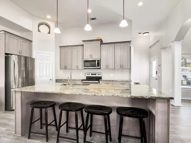 a kitchen with kitchen island granite countertop a table chairs microwave and cabinets