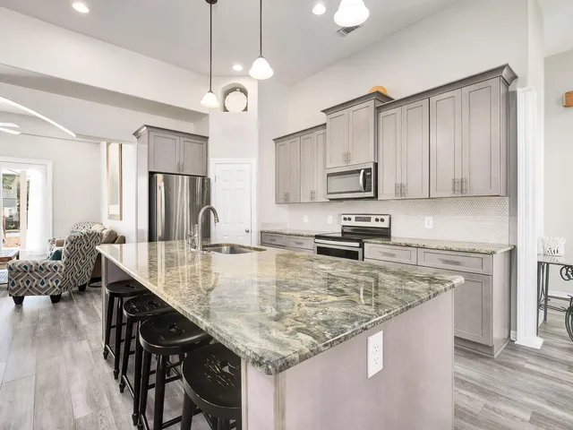 a kitchen with kitchen island granite countertop a sink appliances cabinets and wooden floor