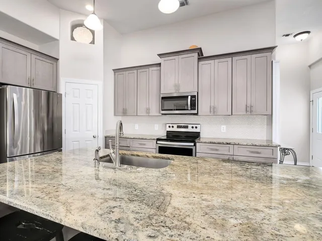 a kitchen with kitchen island granite countertop a sink cabinets and stainless steel appliances