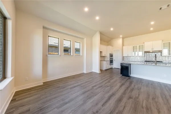 a view of a big room with wooden floor and a kitchen