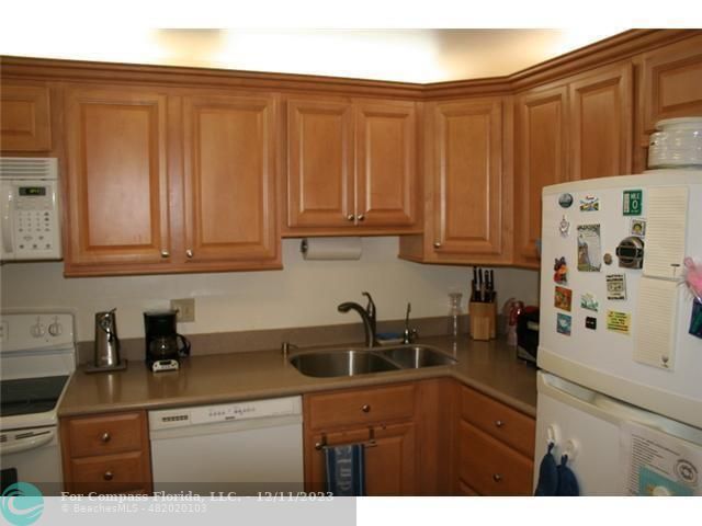 a kitchen with stainless steel appliances granite countertop a sink a stove and dishwasher with wooden cabinets