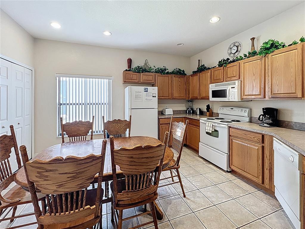 102 Sandy Point Way Clermont, FL 34714 - Photo 7 of 33 a kitchen with stainless steel appliances kitchen island granite countertop a dining table chairs and a refrigerator