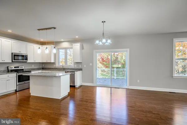 a open kitchen with stainless steel appliances granite countertop a stove top oven a sink dishwasher and wooden floor
