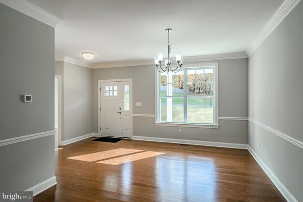 an empty room with wooden floor chandelier and windows