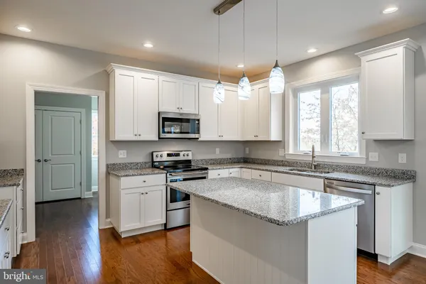 a kitchen with kitchen island granite countertop a sink cabinets and wooden floor
