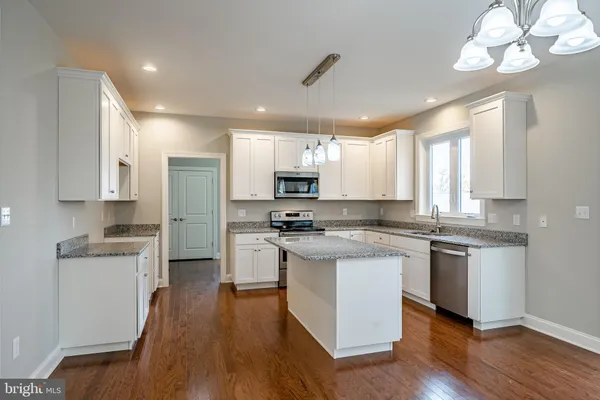 a kitchen with stainless steel appliances granite countertop wooden floors and white cabinets