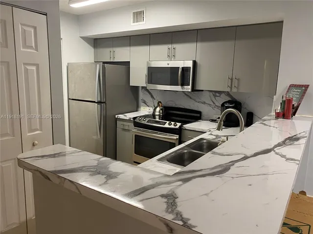 a kitchen with a sink a refrigerator and a stove top oven