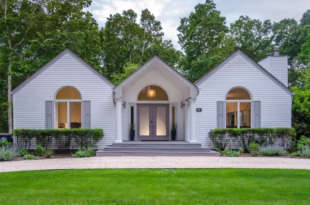 a front view of a house with a yard and potted plants