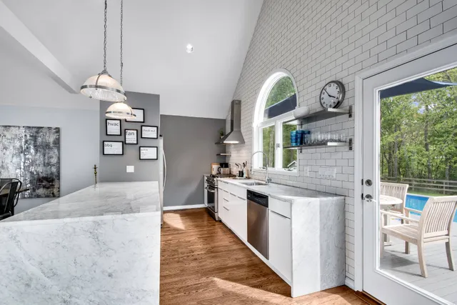 a kitchen with stainless steel appliances granite countertop a stove a sink dishwasher and white cabinets with wooden floor