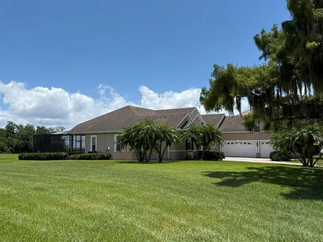 a view of a house with a big yard and palm trees