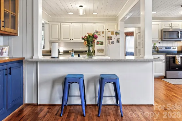 a kitchen with stainless steel appliances kitchen island granite countertop a table chairs sink and cabinets