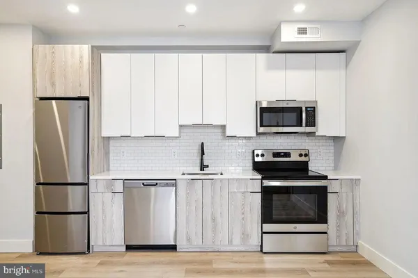 a kitchen with cabinets stainless steel appliances and wooden floor