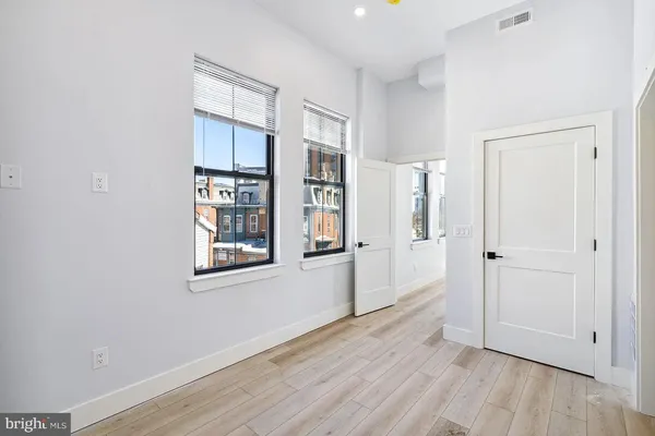 an empty room with wooden floor and windows
