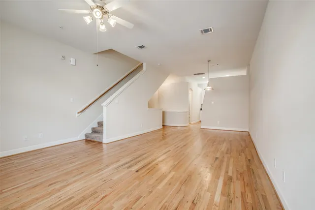 an empty room with wooden floor and staircase