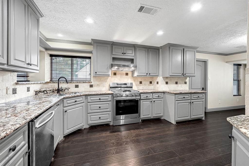 a kitchen with stainless steel appliances sink stove and wooden floor